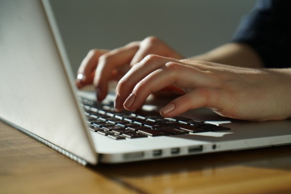 Hands typing on a laptop